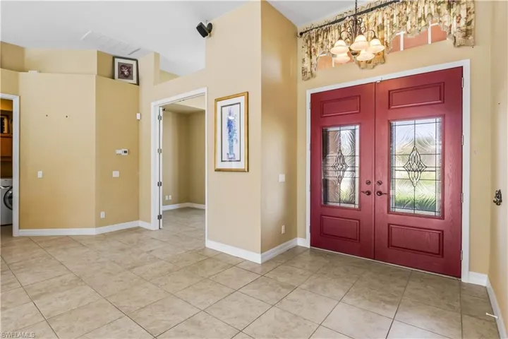 Tiled foyer with french doors, washer / clothes dryer, and a notable chandelier