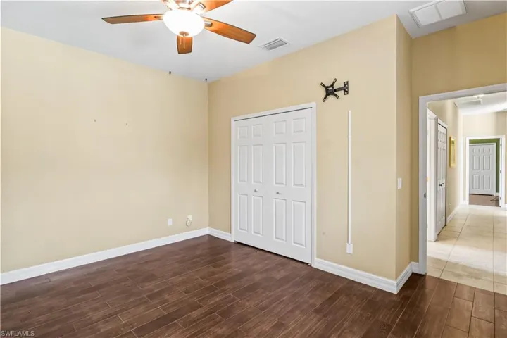 Unfurnished bedroom with ceiling fan, dark hardwood / wood-style flooring, and a closet