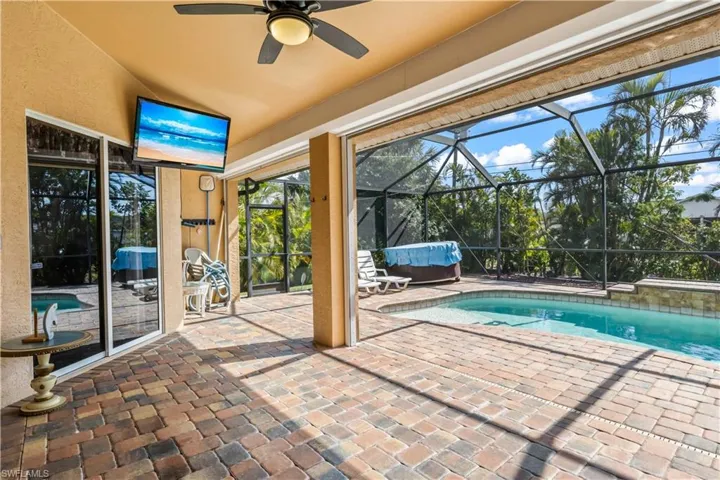 View of swimming pool with a hot tub, a patio area, and a lanai