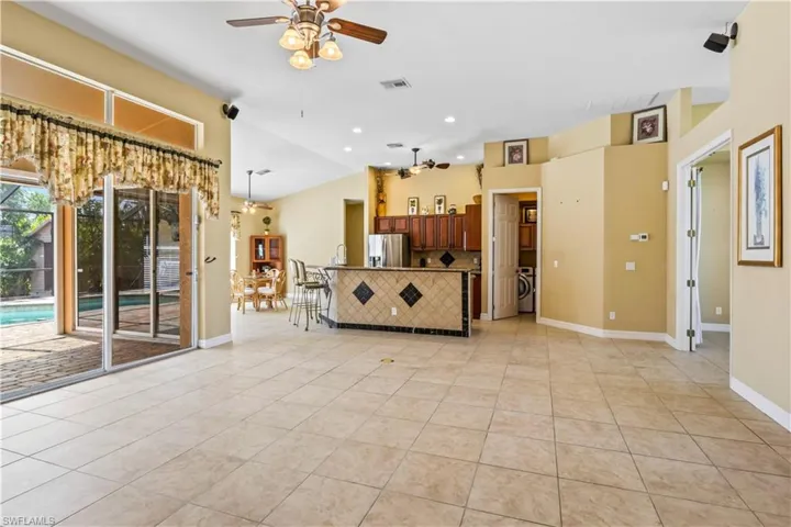 Unfurnished living room featuring washer / clothes dryer, lofted ceiling, light tile patterned floors, and ceiling fan