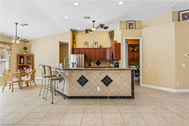 Kitchen with ceiling fan, a kitchen breakfast bar, stainless steel fridge with ice dispenser, and light tile patterned floors