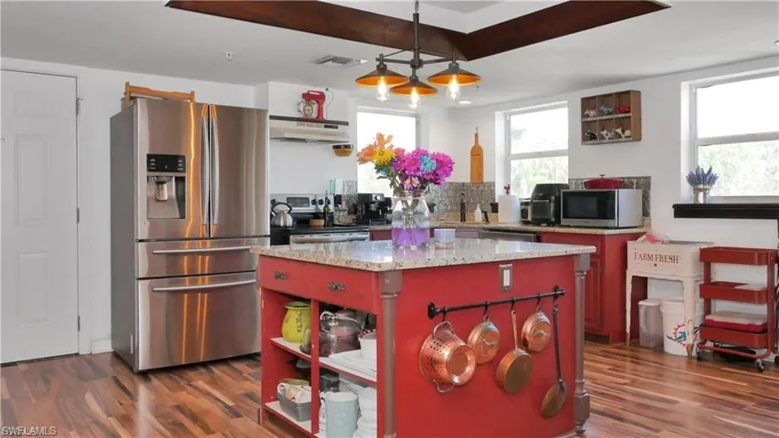 Kitchen featuring open shelves, appliances with stainless steel finishes, pendant lighting, and a kitchen island