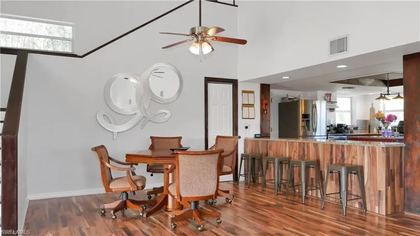 Dining room with a ceiling fan, dark wood-type flooring, and a high ceiling
