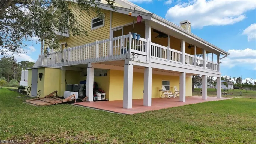 Back of property with a yard, stucco siding, a wooden deck, and a chimney