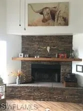 large fireplace, wood finished floors, butcher block countertops, and white cabinetry