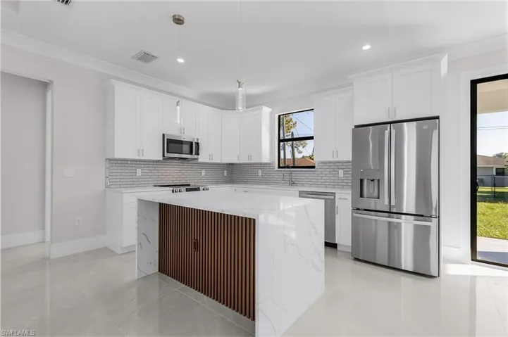 Kitchen featuring white cabinets, decorative backsplash, a center island, and stainless steel appliances