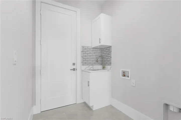 Laundry area featuring cabinets, hookup for a washing machine, light tile patterned floors, and sink