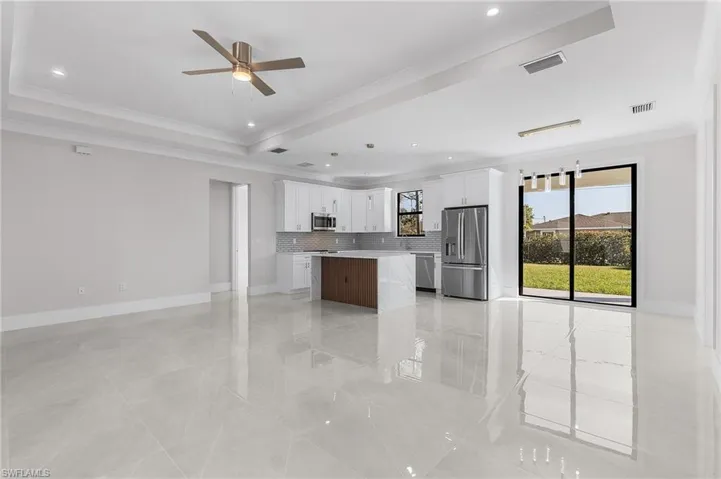 Kitchen with decorative backsplash, a center island, white cabinetry, and appliances with stainless steel finishes