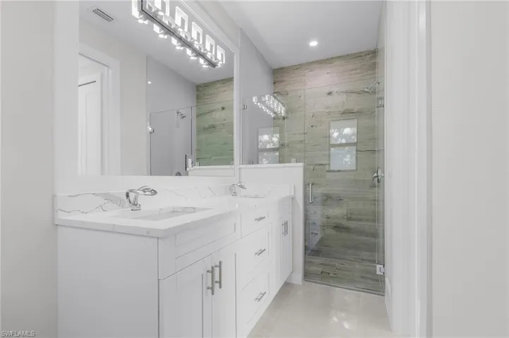 Bathroom featuring tile patterned flooring, vanity, and an enclosed shower