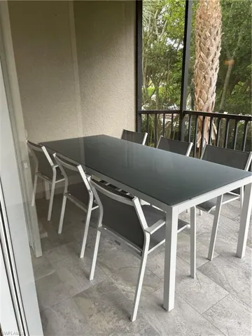 Screened-in balcony featuring tiled flooring and black metal railing
