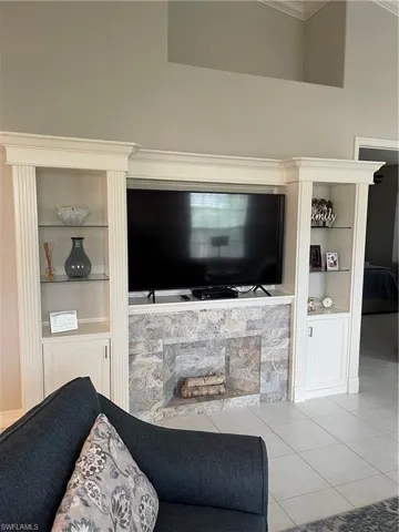 Custom floor-to-ceiling cabinetry with fluted detailing, glass display shelving, and base storage, centered by a stone-faced fireplace surround