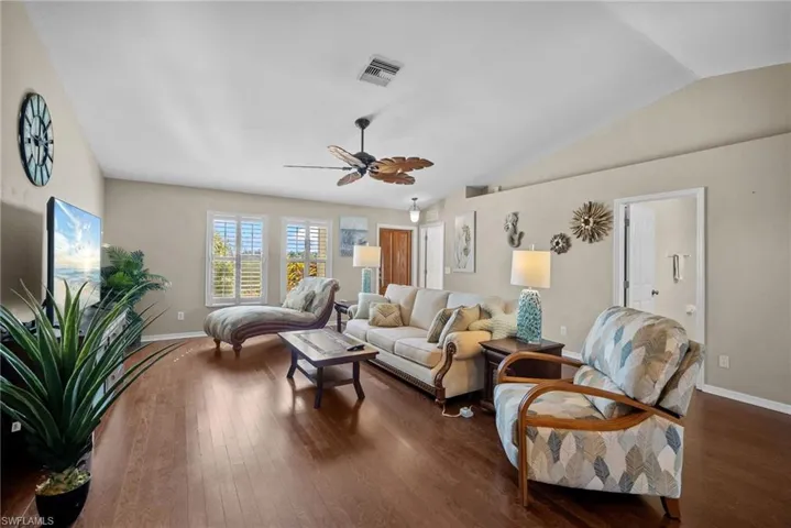 Living room with ceiling fan, hardwood / wood-style floors, and vaulted ceiling