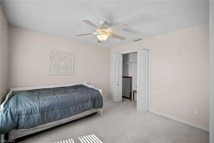 Carpeted bedroom featuring a ceiling fan and a closet