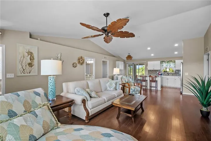Living area with dark wood-type flooring, recessed lighting, lofted ceiling, and ceiling fan