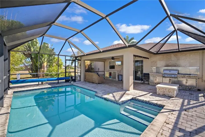 Outdoor pool with a sunroom, a patio, a lanai, and an outdoor kitchen