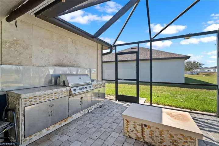 View of patio with glass enclosure, area for grilling, and a sunroom
