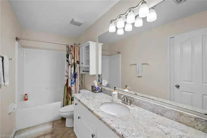 Bathroom featuring vanity, shower / bath combo, and light tile patterned floors
