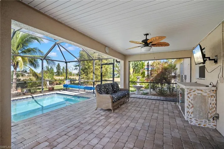 Swimming pool with a sunroom, a patio area, and glass enclosure