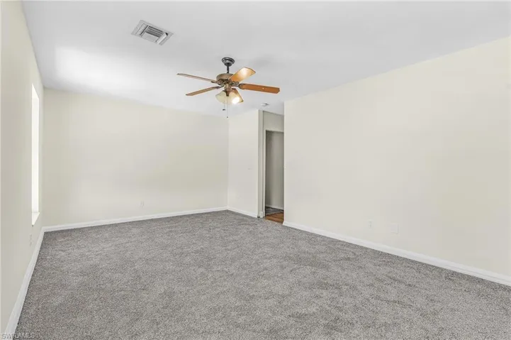 Neutral wall color with gray carpeting, featuring a ceiling fan with integrated lighting