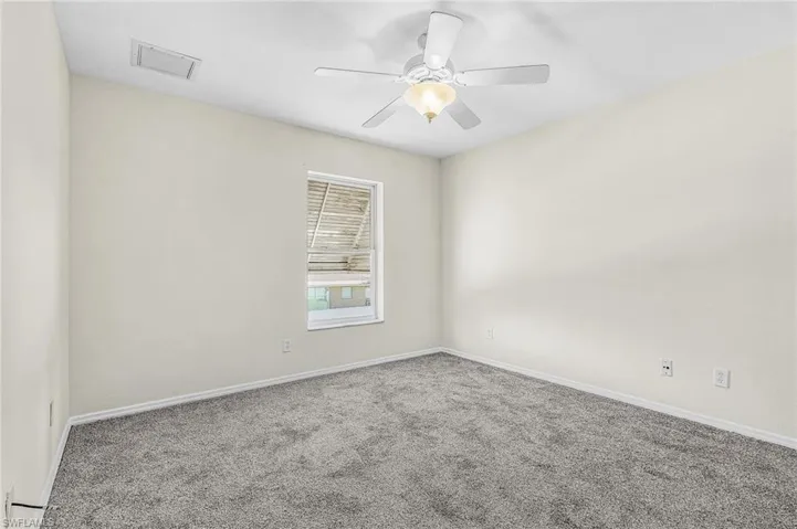Recessed window with blinds, ceiling fan with light fixture, and gray carpeting