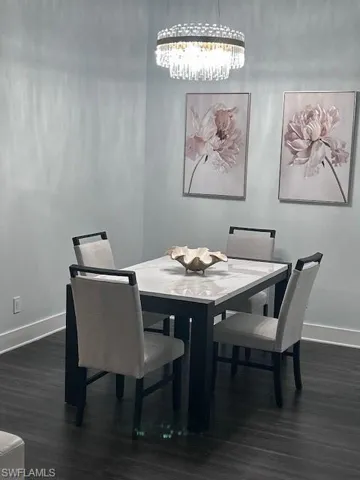 Dining area with dark wood-type flooring and a chandelier