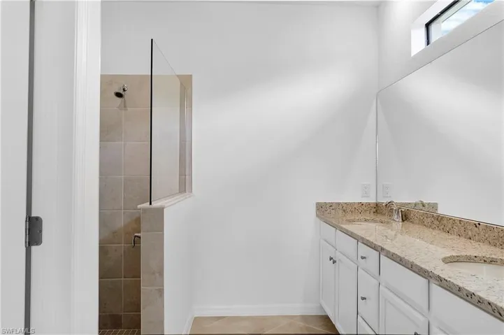 Full bathroom with double vanity, a shower stall, and light tile patterned floors