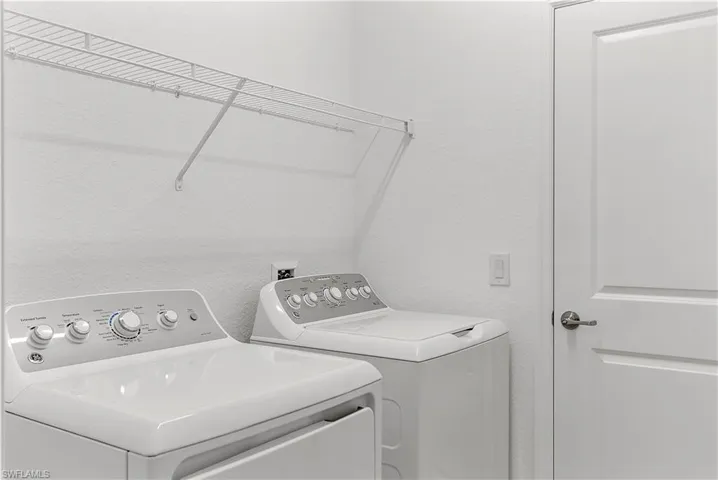 Laundry room with a textured wall and washer and clothes dryer
