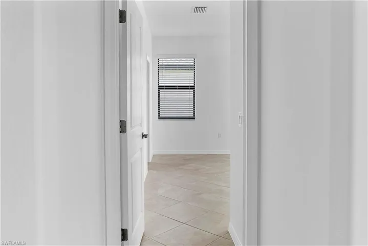 Corridor with light tile patterned flooring and baseboards