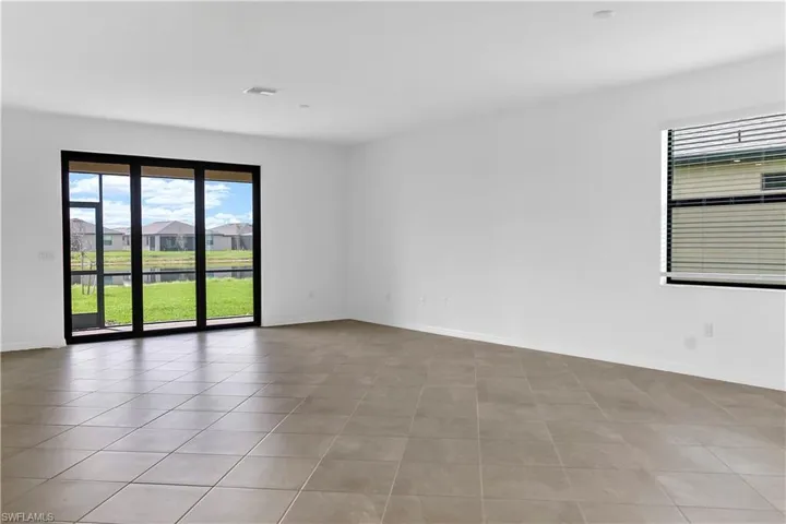 Spare room with light tile patterned floors, healthy amount of natural light, a water view, and a residential view