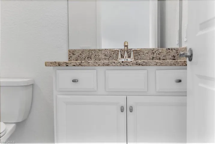 Bathroom featuring a textured wall and vanity