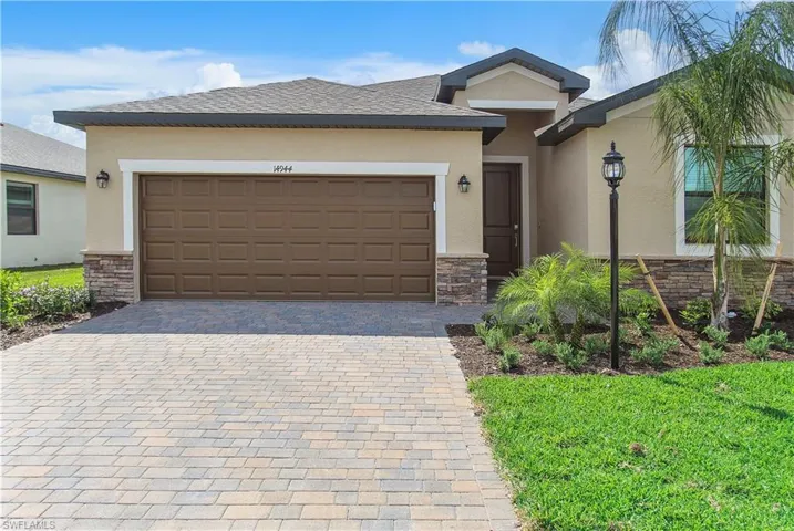 View of front of house featuring stone siding, decorative driveway, stucco siding, and a garage