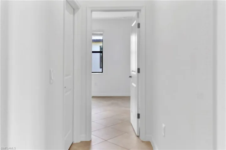 Corridor featuring light tile patterned flooring and baseboards
