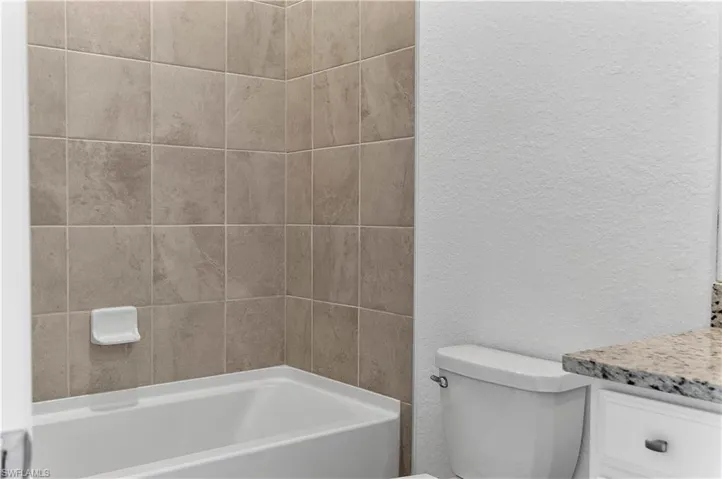 Full bathroom with a textured wall, vanity, and bathing tub / shower combination