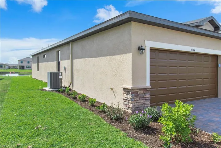 View of property exterior with stone siding, stucco siding, a yard, and driveway