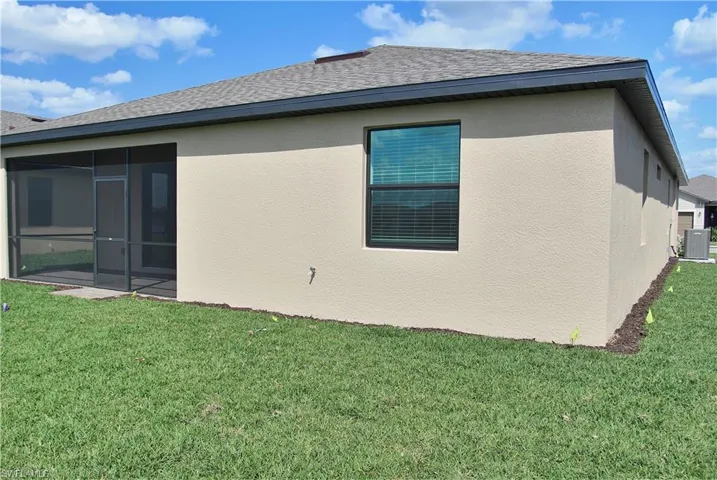 Back of house with a yard, a sunroom, roof with shingles, and stucco siding