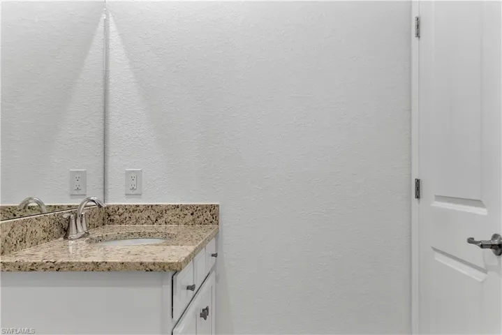 Bathroom featuring a textured wall and vanity