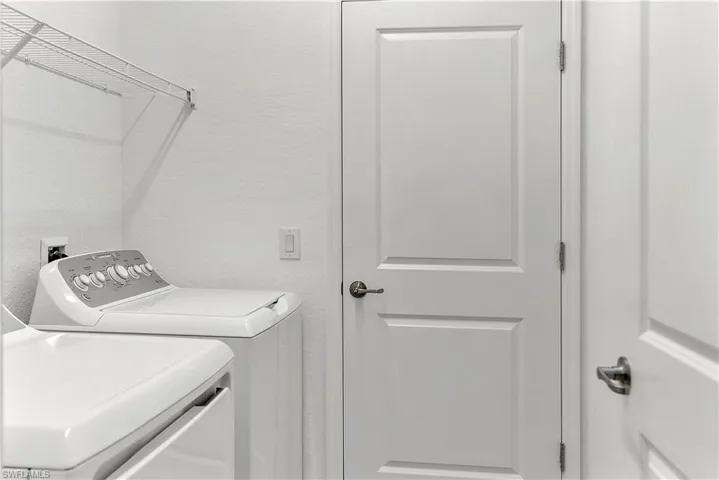 Laundry area featuring a textured wall and washing machine and clothes dryer
