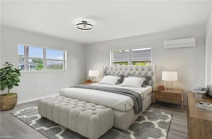 Bedroom with wood finished floors, multiple windows, and a wall mounted air conditioner