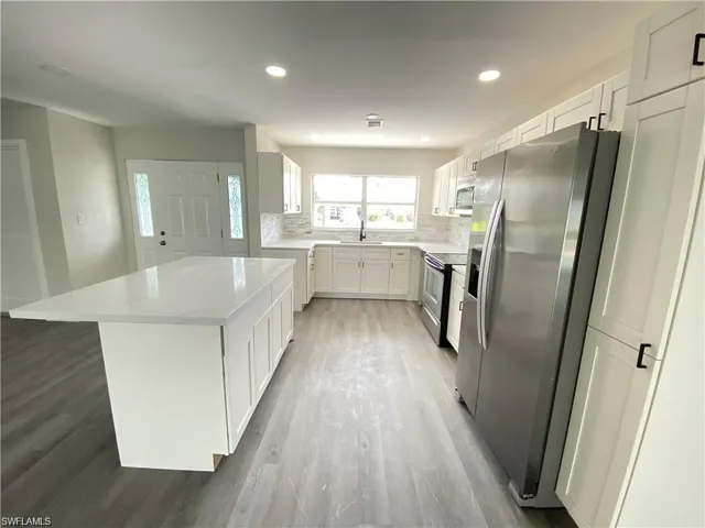 Kitchen featuring stainless steel appliances, backsplash, white cabinets, recessed lighting, and a center island