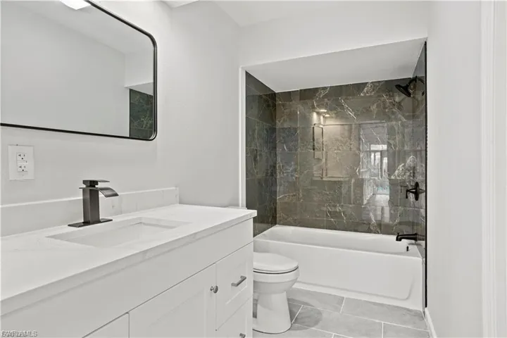 Bathroom with shower / bath combination, vanity, and light tile patterned floors