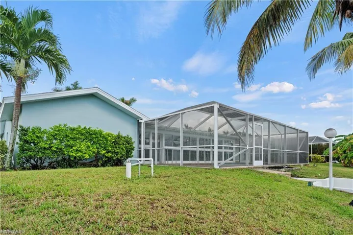 Rear view of property featuring a sunroom, glass enclosure, a yard, and stucco siding