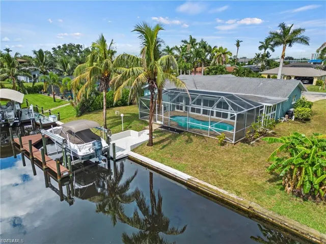 Dock featuring boat lift, a lawn, a sunroom, an outdoor pool, and glass enclosure