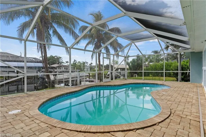 Outdoor pool featuring a patio area, a sunroom, glass enclosure, and a dock