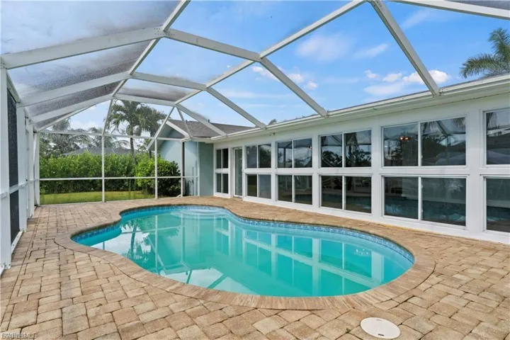 Outdoor pool featuring a sunroom, a patio, and a lanai