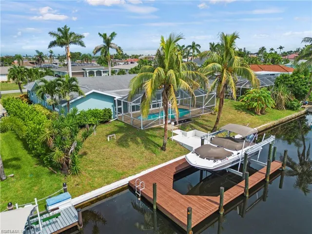 Dock area featuring boat lift, a lawn, a sunroom, and a water view