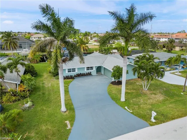 View of front of property with concrete driveway, a front yard, an attached garage, and a residential view