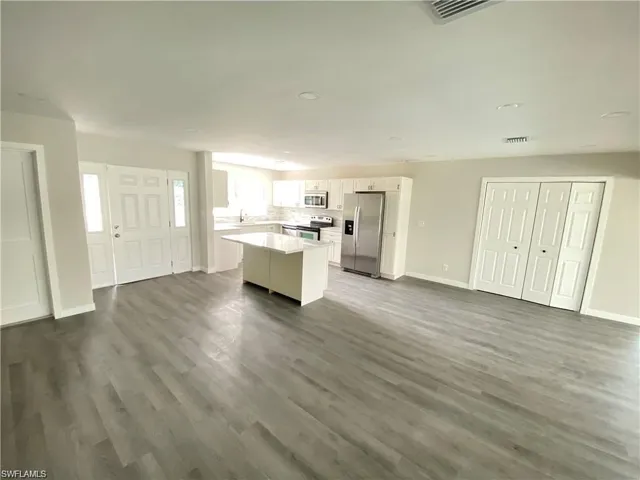 Kitchen with open floor plan, white cabinetry, appliances with stainless steel finishes, light countertops, and recessed lighting
