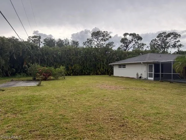View of grassy yard featuring a sunroom