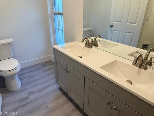 Full bath featuring wood finished floors and double vanity