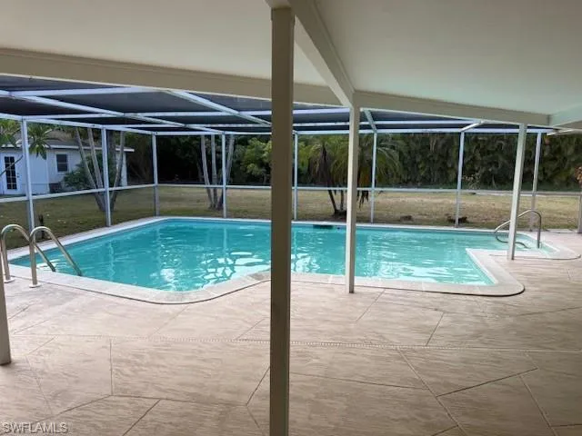 Outdoor pool featuring a patio area, glass enclosure, and a yard
